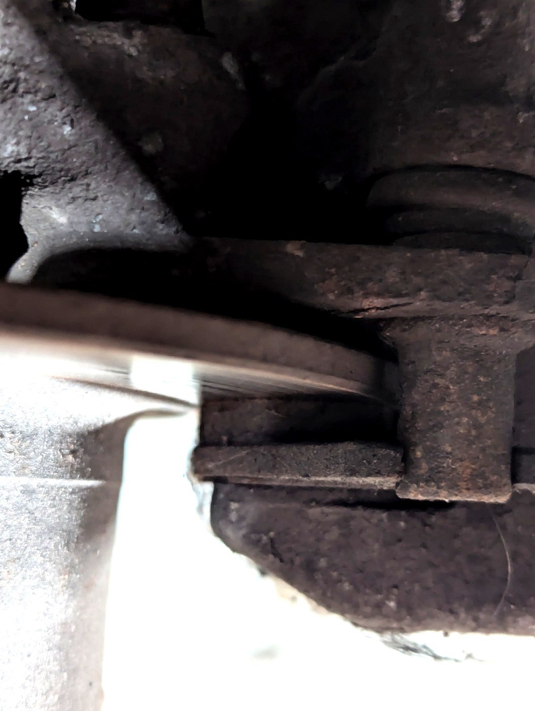 The front brake caliper and disc photographed with the road wheel removed, the edge
                of the brake pad visible in the gap between caliper and disc