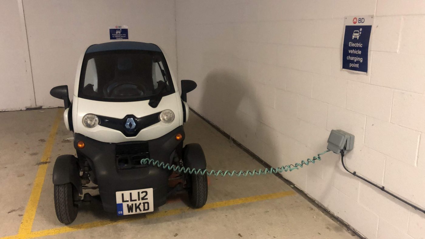 The Twizy plugged into a 13 amp socket in a marked electric vehicle bay in an
                underground car park