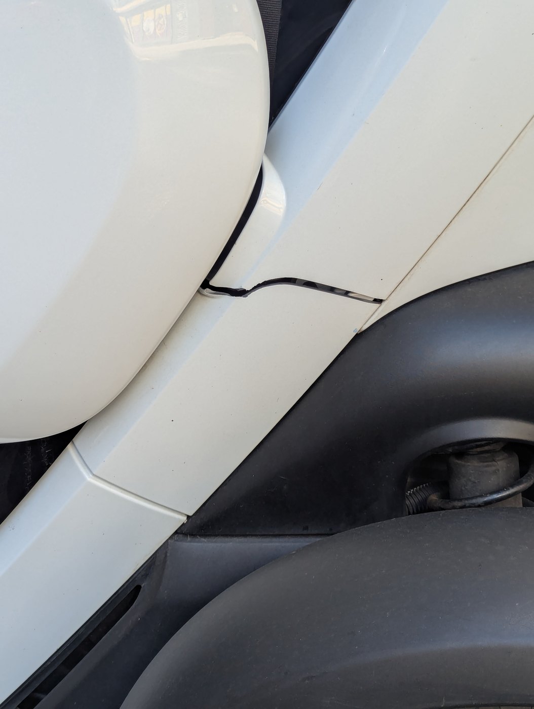 A crack running horizontally through the white nearside body panel, below the door
                mirror