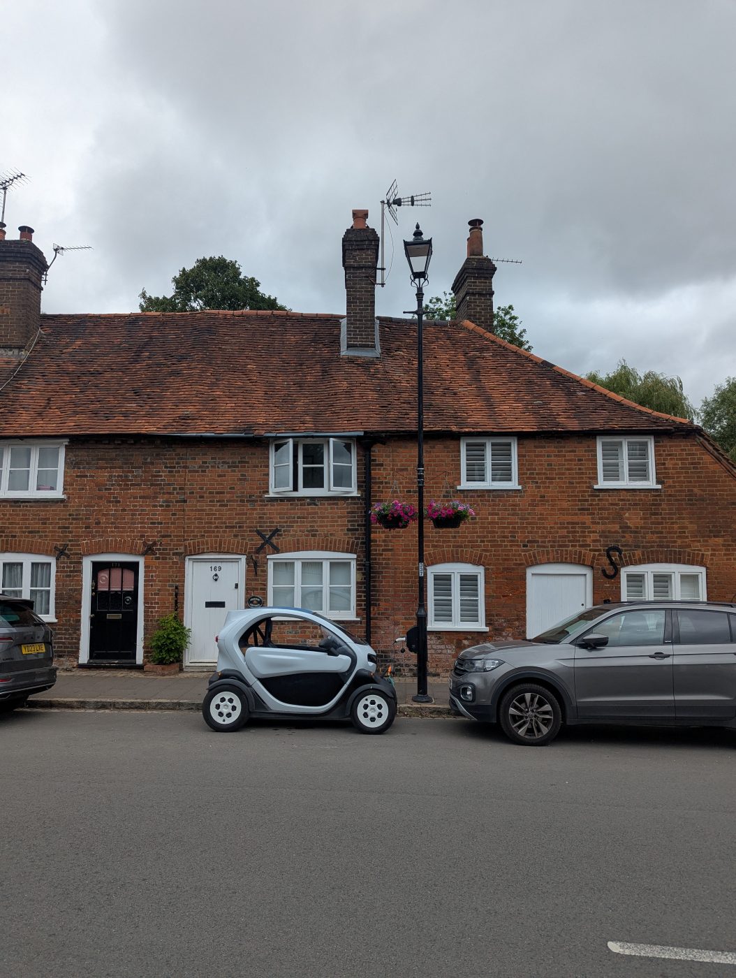 The Twizy parked side-on between a hatchback and a VW T-Cross, showing how much
                shorter it is than both